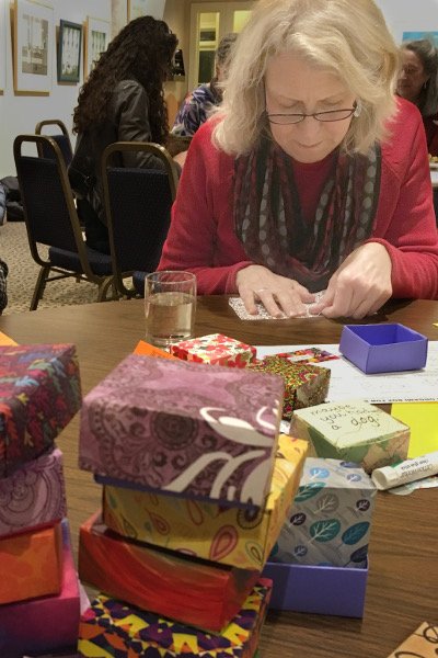 Event: Folding Soul Boxes Woman folds a Soul Box to add to a stack